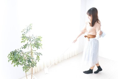 Genç bir kadın odasını temizliyor.