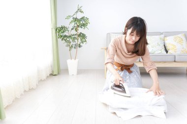 Elbiselerini ütüleyen genç kadın.