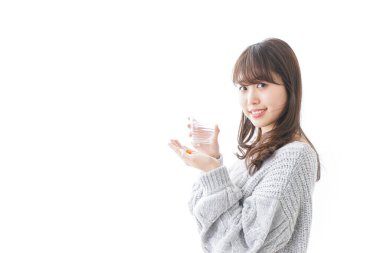 Genç bir kadın hap yutuyor.