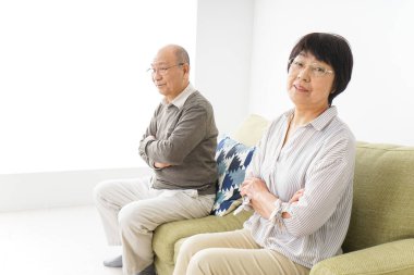 Yaşlı Asyalı çift evdeki kanepede oturuyor.