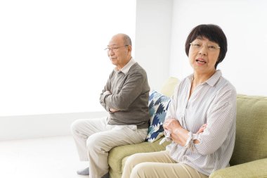 Yaşlı Asyalı çift evdeki kanepede oturuyor.