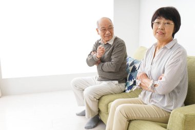 Yaşlı Asyalı çift evdeki kanepede oturuyor.