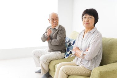 Yaşlı Asyalı çift evdeki kanepede oturuyor.