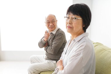 Yaşlı Asyalı çift evdeki kanepede oturuyor.