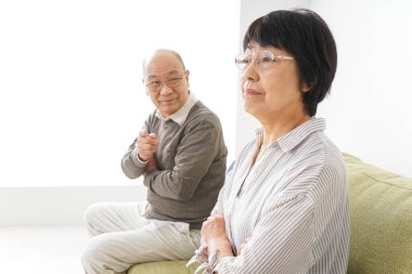 Yaşlı Asyalı çift evdeki kanepede oturuyor.