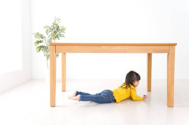 Masanın altına kıvrılmış çocuk