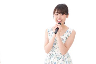 Genç bir kadın mikrofonla karaoke yapıyor. 