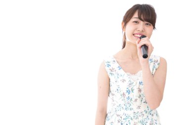 Genç bir kadın mikrofonla karaoke yapıyor. 