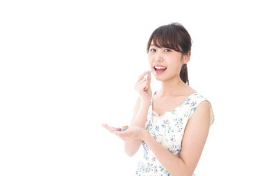 Tatlı yiyen ve beyaz arka planda yalnız poz veren genç bir kadın.