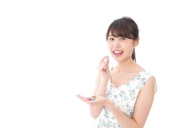 Tatlı yiyen ve beyaz arka planda yalnız poz veren genç bir kadın.