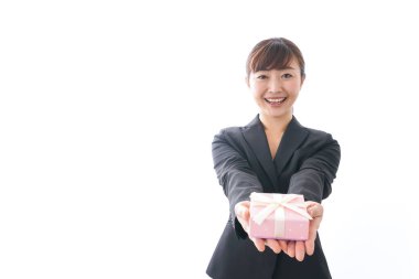 Takım elbiseli genç bir kadın beyaz arka planda hediye kutusu tutuyor.,