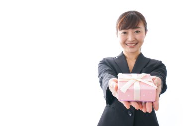 Takım elbiseli genç bir kadın beyaz arka planda hediye kutusu tutuyor.,