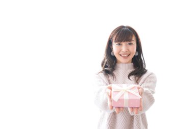 Takım elbiseli genç bir kadın beyaz arka planda hediye kutusu tutuyor.,
