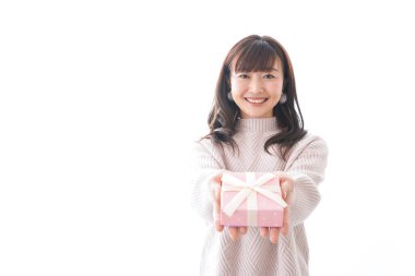 Takım elbiseli genç bir kadın beyaz arka planda hediye kutusu tutuyor.,