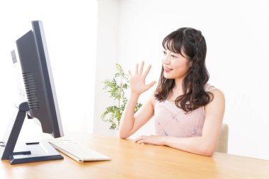 Evde görüntülü konuşma yapan genç bir kadın.