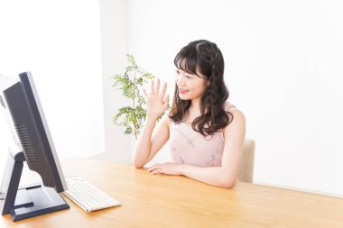 Evde görüntülü konuşma yapan genç bir kadın.