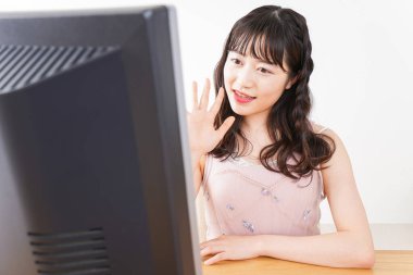 Evde görüntülü konuşma yapan genç bir kadın.