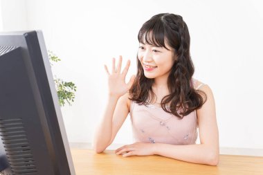 Evde görüntülü konuşma yapan genç bir kadın.