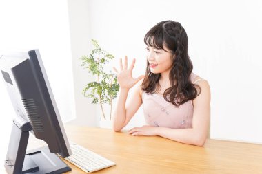 Evde görüntülü konuşma yapan genç bir kadın.