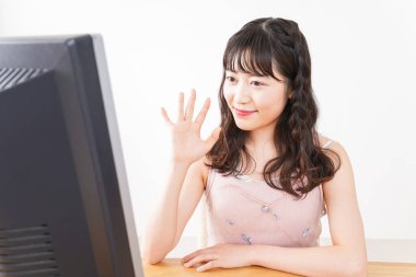 Evde görüntülü konuşma yapan genç bir kadın.