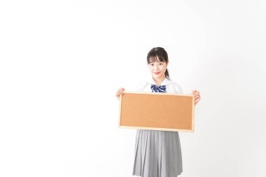 Genç Asyalı bir kız öğrenci elinde bir pano tutuyor.