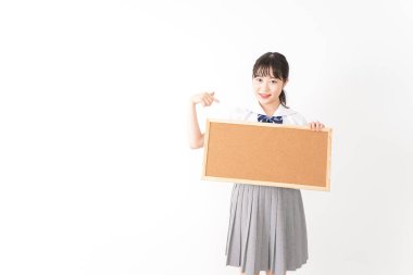 Genç Asyalı bir kız öğrenci elinde bir pano tutuyor.