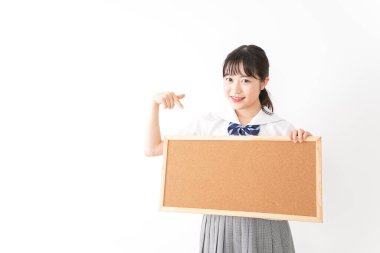 Genç Asyalı bir kız öğrenci elinde bir pano tutuyor.