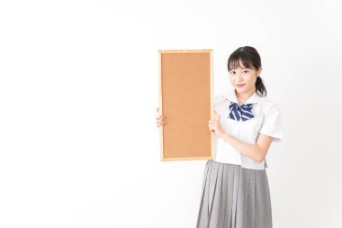 Genç Asyalı bir kız öğrenci elinde bir pano tutuyor.