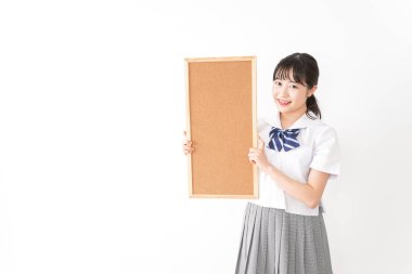 Genç Asyalı bir kız öğrenci elinde bir pano tutuyor.