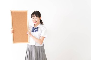 Genç Asyalı bir kız öğrenci elinde bir pano tutuyor.