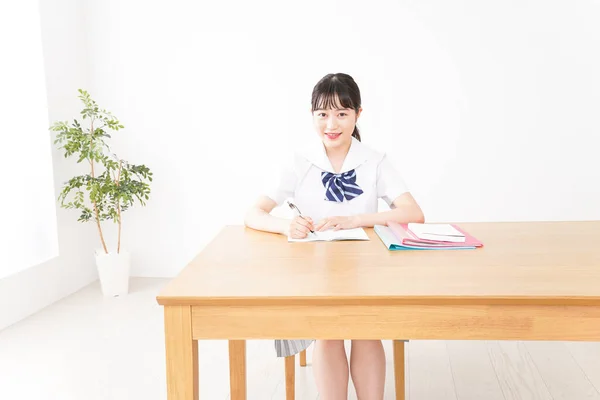 young Asian female student in uniform studying