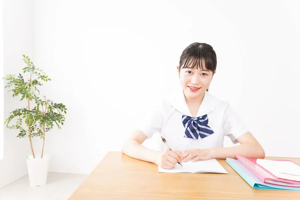 young Asian female student in uniform studying