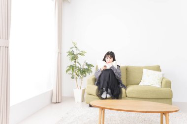 Evde televizyon izleyen genç bir kadın.