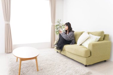 Evde televizyon izleyen genç bir kadın.