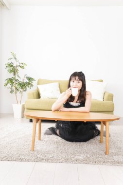 Asyalı kadın evde kahve içiyor.