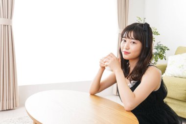 Asyalı kadın evde kahve içiyor.