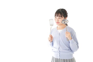 Arka planda yemek yapan genç bir kadın.