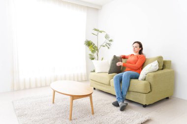 Evde televizyon izleyen genç bir kadın.