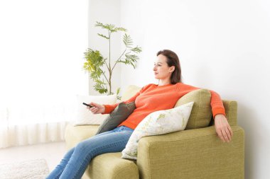 Evde televizyon izleyen genç bir kadın.