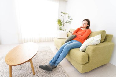 Evde televizyon izleyen genç bir kadın.