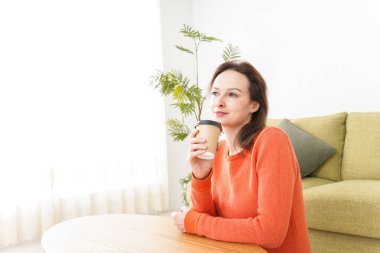 Genç bayan evde kahve içiyor.