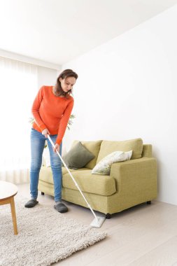 Genç bir kadın evini temizliyor.