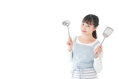 Genç bir kadın mutfak aletlerini beyaz arka planda tutuyor.