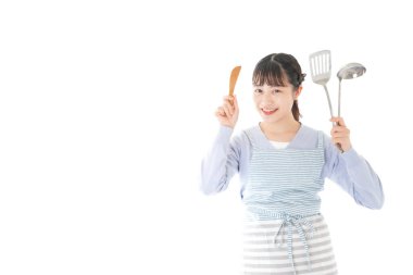 Mutfak aletleri tutan genç bir kadın.