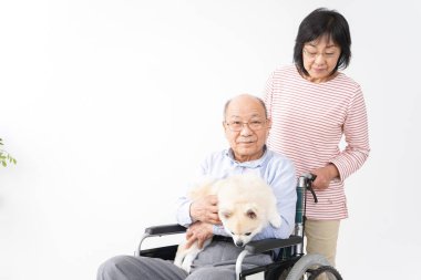 Tekerlekli sandalyede kocasıyla ilgilenen yaşlı bir kadın.