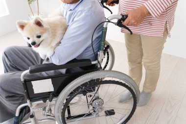 Tekerlekli sandalyede kocasıyla ilgilenen yaşlı bir kadın.