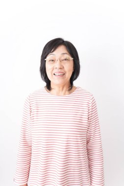 Yaşlı kadın beyaz arka planda gülümsüyor.