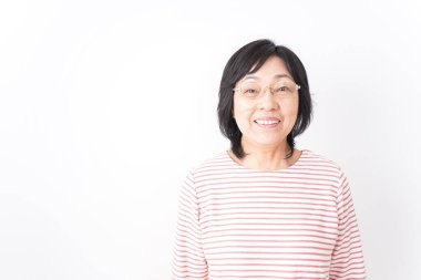 Yaşlı kadın beyaz arka planda gülümsüyor.