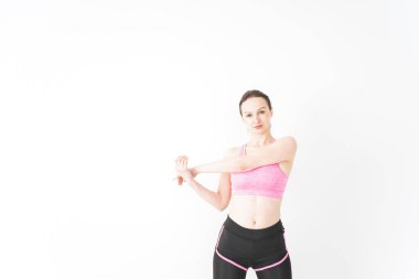 Spor giyinen genç bir kadın esneme hareketleri yapıyor.