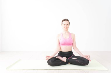 Gülümseyerek yoga yapan genç bir kadın.